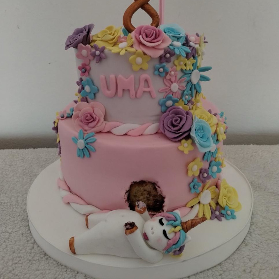 Torta de unicornio de dos pisos en rosa con flores de azúcar en tonos pastel